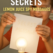 Kid holding invisible ink message over light bulb to reveal writing