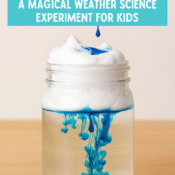 Rain in a Jar science experiment showing blue colored water dripping through shaving cream into a clear jar of water